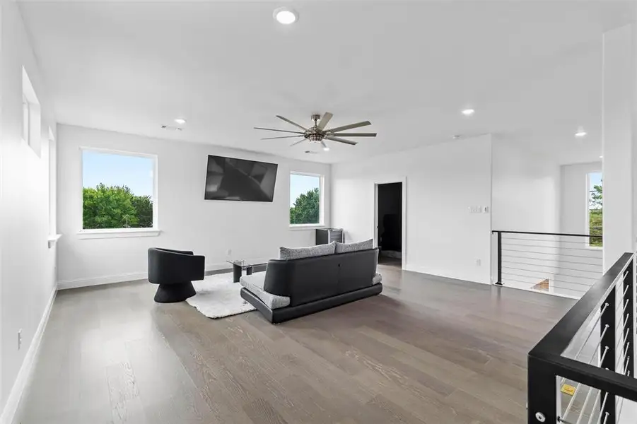 Spacious room featuring wood-finish flooring, recessed lighting, and a modern ceiling fan