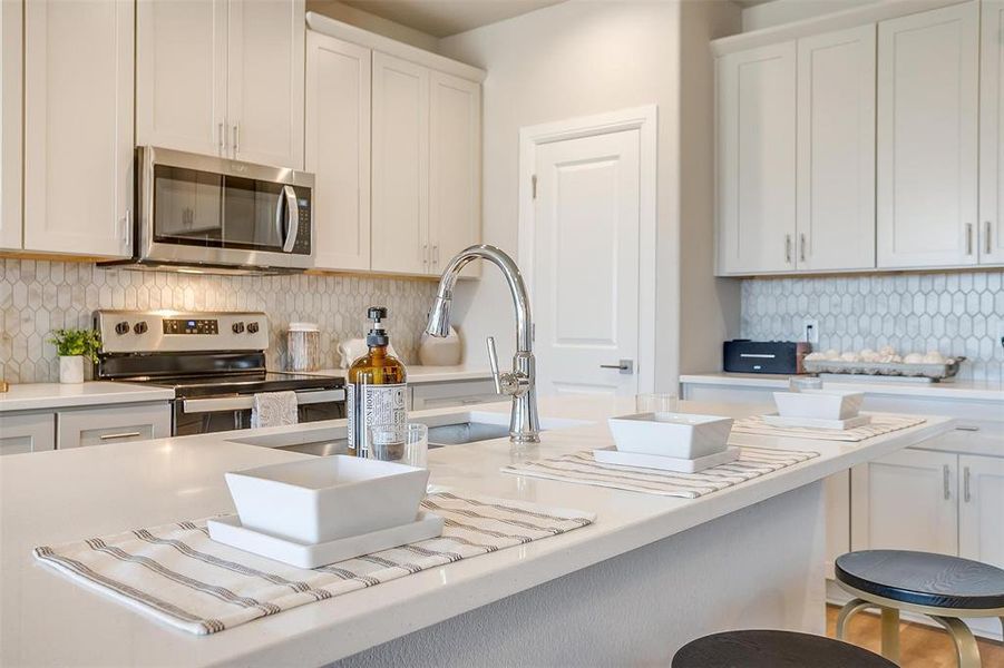 Kitchen featuring appliances with stainless steel finishes, decorative backsplash, and white cabinetry