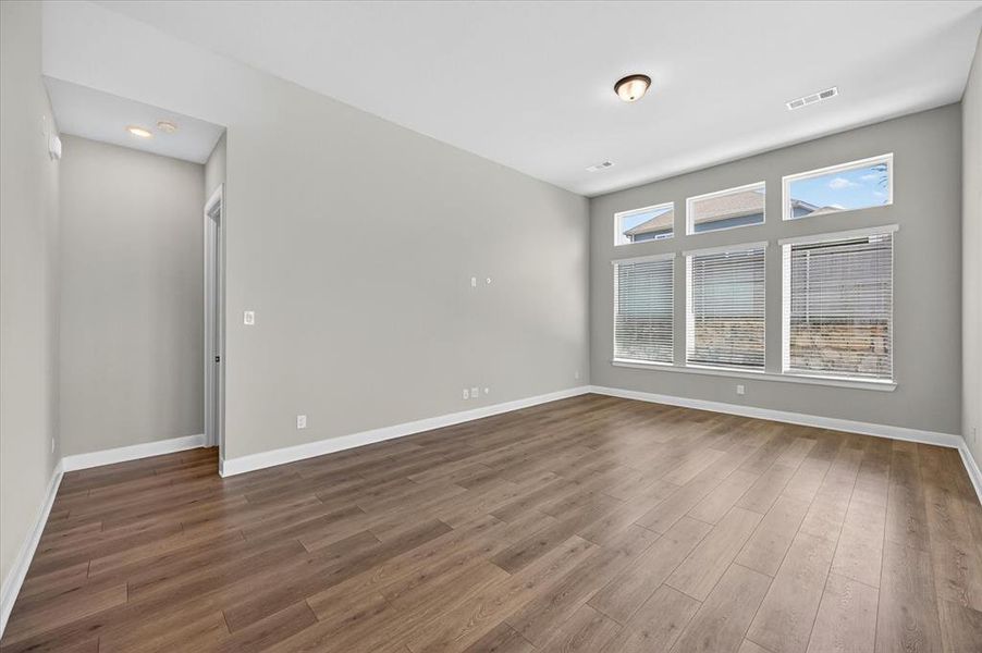 Spacious room featuring wood-finish flooring, light gray walls, and white trim Spacious room featuring wood-finish flooring, light gray walls, and white trim