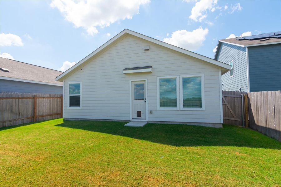 Rear exterior featuring light-colored siding, a gabled roofline, and multiple windows