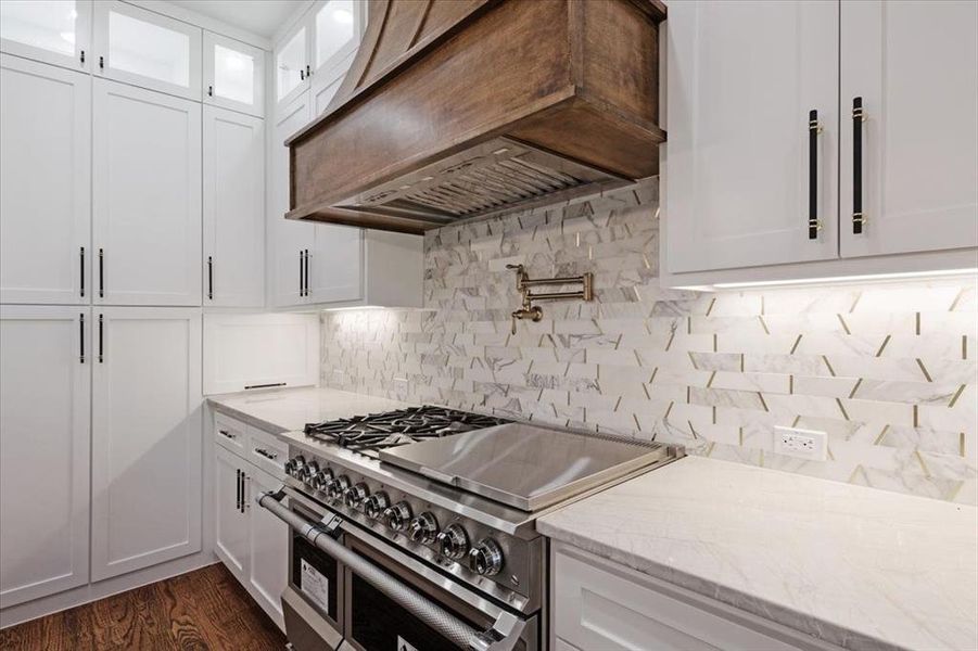 Kitchen featuring dark hardwood / wood-style flooring, range with two ovens, backsplash, white cabinetry, and premium range hood