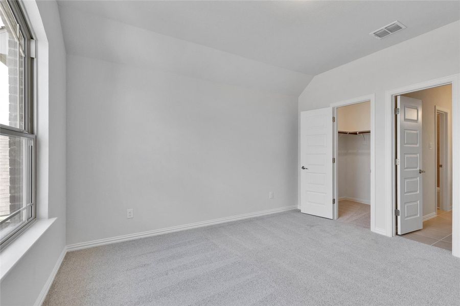 Unfurnished bedroom with a spacious closet, light colored carpet, and vaulted ceiling Unfurnished bedroom with a spacious closet, light colored carpet, and vaulted ceiling