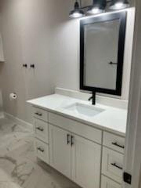 Primary bathroom featuring stylish vanity, mirror and light fixture