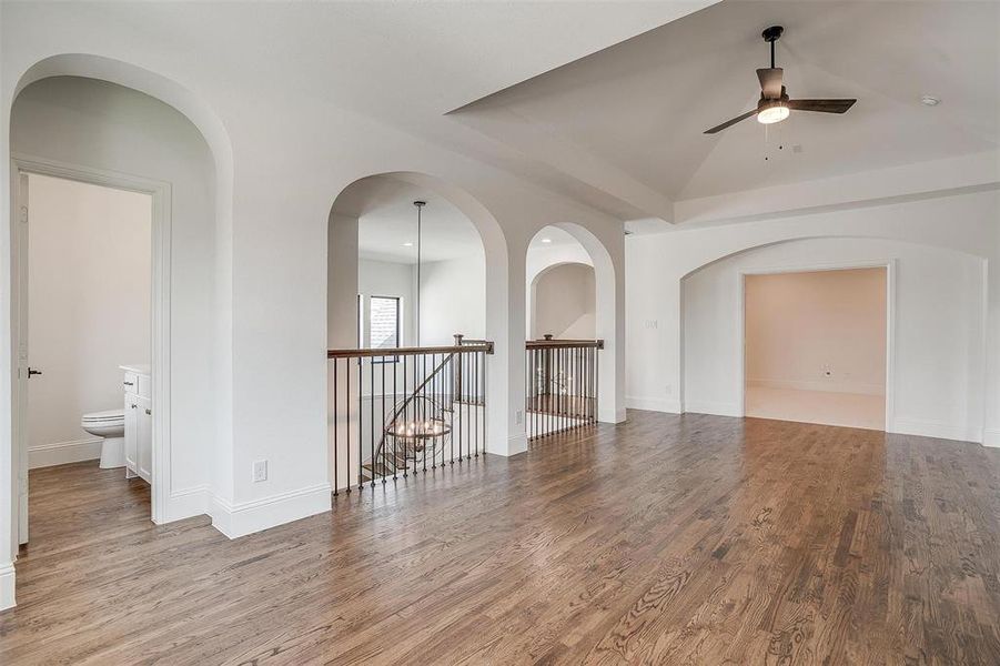 Spare room with ceiling fan, vaulted ceiling, and wood-type flooring