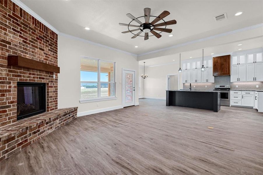 Kitchen with hardwood / wood-style floors, decorative light fixtures, a fireplace, decorative backsplash, and stainless steel range with electric stovetop