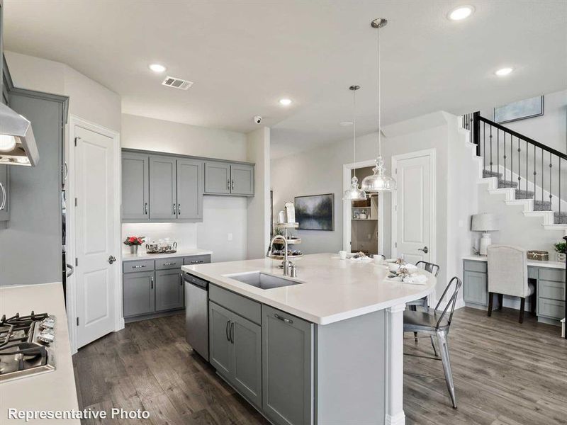 Kitchen with gray cabinetry, sink, dark hardwood / wood-style floors, and a center island with sink