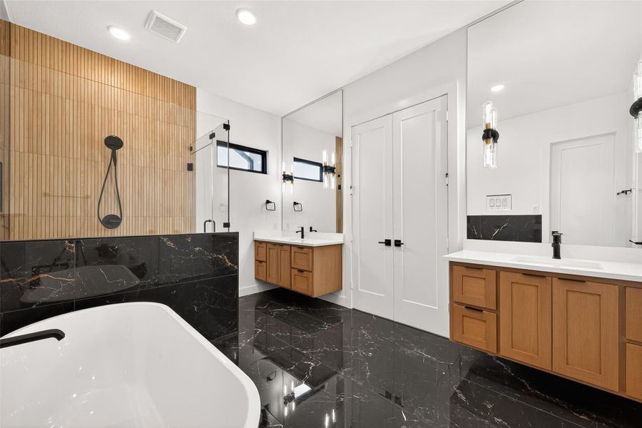 Primary 2 ensuite: Highlights include freestanding soaking tub, oversized walk-in shower, dual floating vanities, luxurious black floors, gold hardware finishes, and walk-in closet.