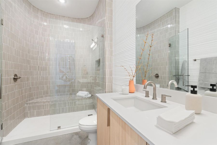 Bathroom featuring toilet, vanity, and a shower