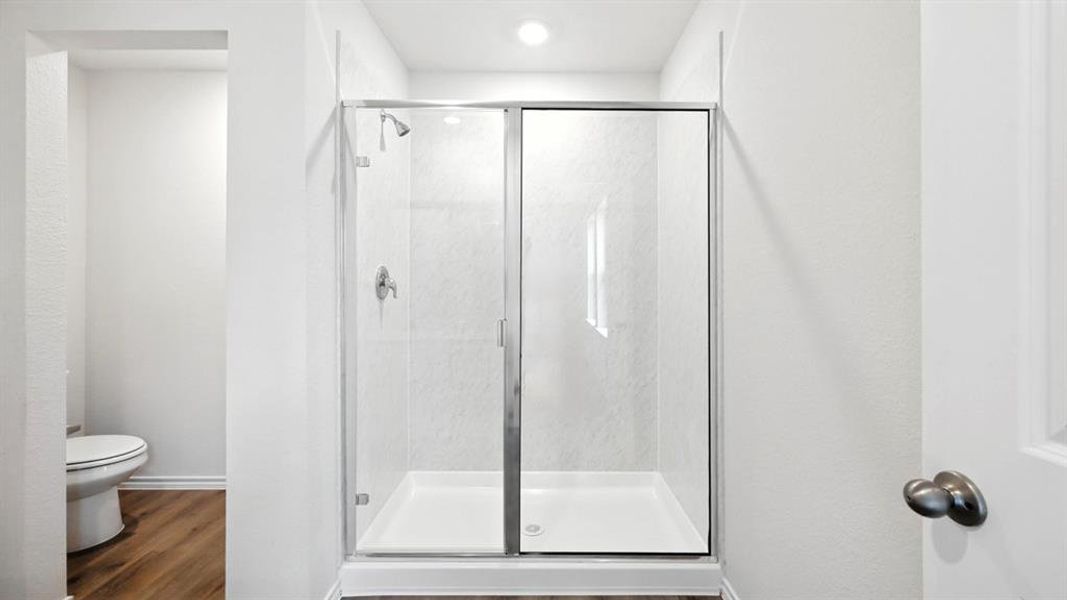 Glass-enclosed shower with a white tiled surround and chrome fixtures Glass-enclosed shower with a white tiled surround and chrome fixtures