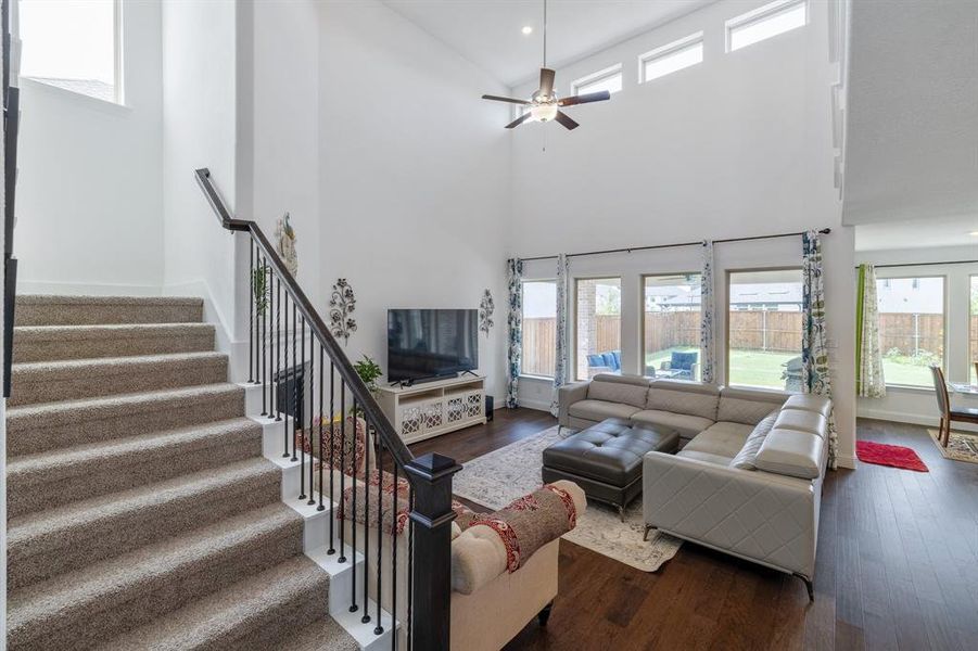 Living area featuring stairway, wood finished floors, a towering ceiling, and recessed lighting