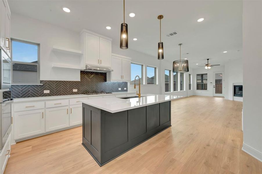 Modern kitchen featuring white cabinetry, a dark herringbone tile backsplash, and a large central island with a light-colored countertop