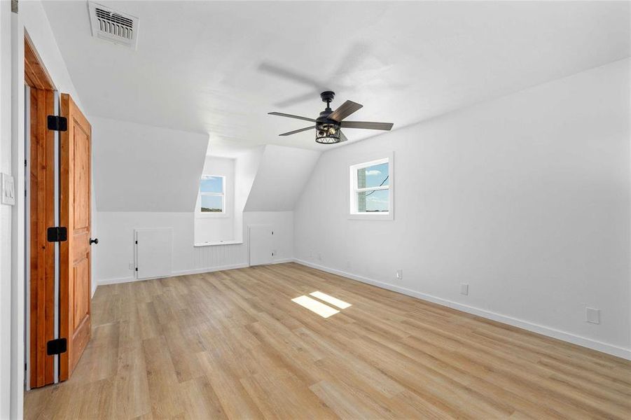 Additional living space featuring lofted ceiling, light wood-style flooring, and ceiling fan