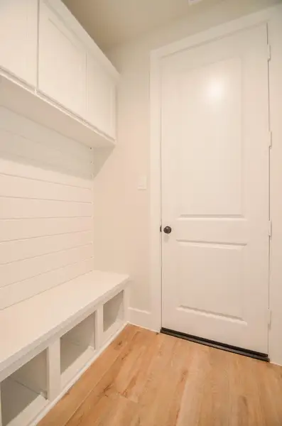 A thoughtfully designed mudroom with built-in bench seating, cubby storage below, and overhead cabinetry. The shiplap wall paneling adds character, while the space offers a convenient drop zone for shoes, bags, and coats. Located just off the garage entry, it's the perfect blend of practicality and charm.