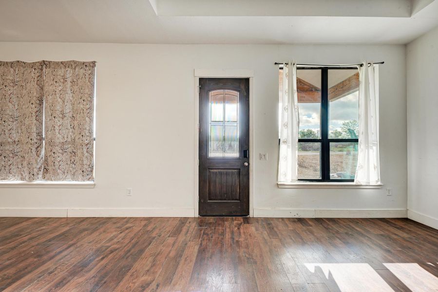 Rich wood floors and a glass-paneled entry door anchor this versatile open room.