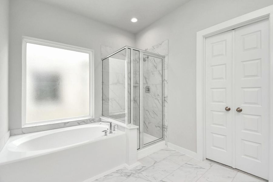 Enjoy a walk-in shower with tile surround, a separate garden tub with custom detailing. Sample photo of completed home with similar floor plan. Actual colors and selections may vary.