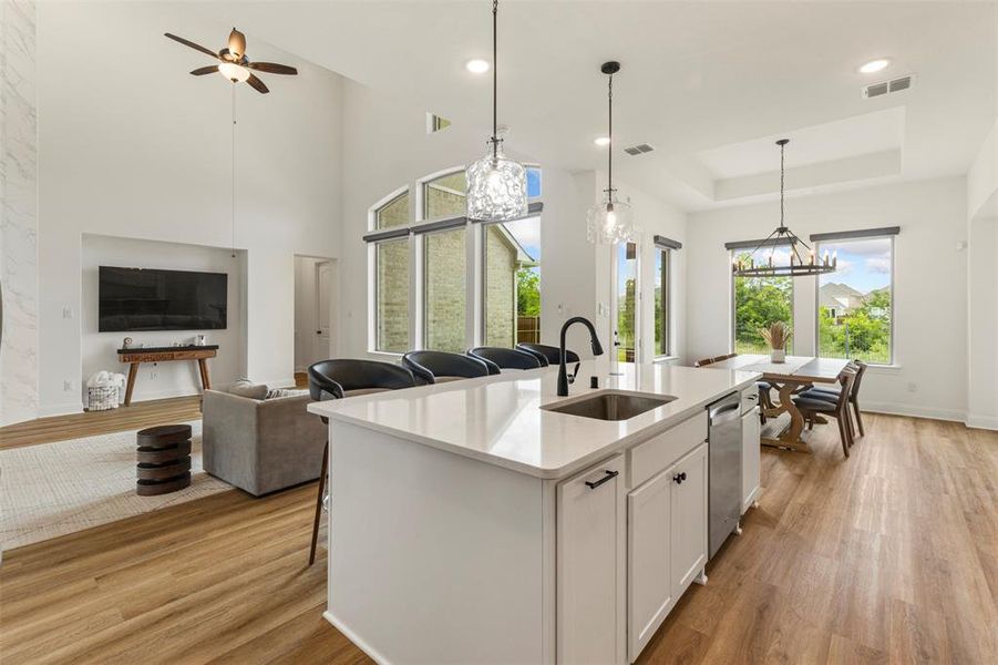 Kitchen featuring light wood-style floors, open floor plan, a chandelier, a tray ceiling, and recessed lighting Kitchen featuring light wood-style floors, open floor plan, a chandelier, a tray ceiling, and recessed lighting