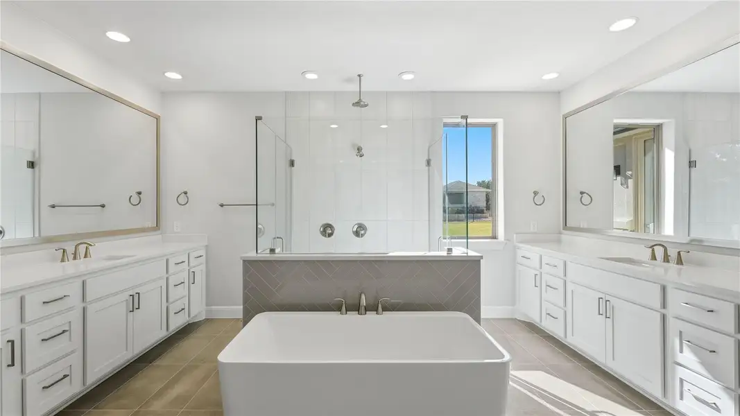 Bathroom featuring a shower stall, two vanities, a freestanding bath, light tile patterned floors, and recessed lighting Bathroom featuring a shower stall, two vanities, a freestanding bath, light tile patterned floors, and recessed lighting