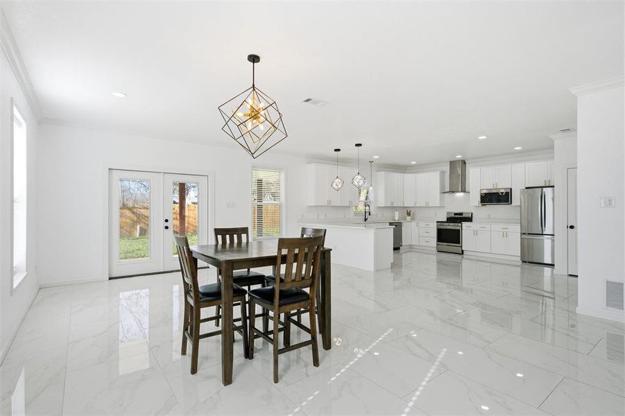 Dining room featuring french doors, light marble finish floors, recessed lighting, a chandelier, and ornamental molding Dining room featuring french doors, light marble finish floors, recessed lighting, a chandelier, and ornamental molding
