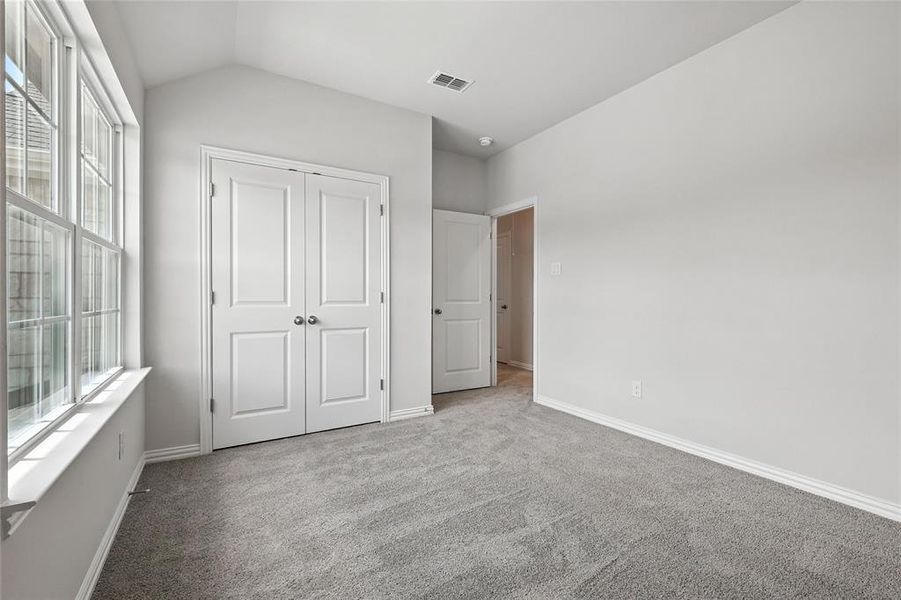 Unfurnished bedroom with carpet, vaulted ceiling, and a closet