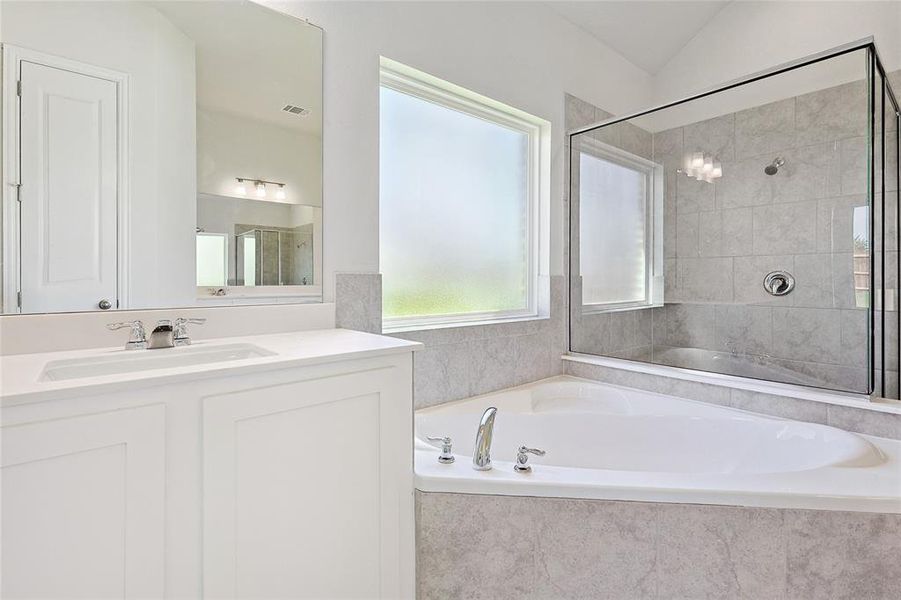 Bathroom with independent shower and bath, vaulted ceiling, and vanity