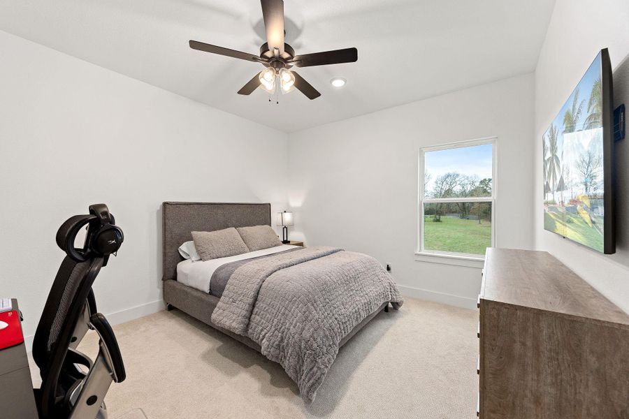 This secondary bedroom features high ceilings, beautiful modern ceiling fan, neutral paint, plush carpet, and a large window that provides natural light.