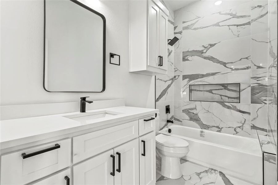 Full bath featuring vanity, shower / tub combination, and marble look tile flooring