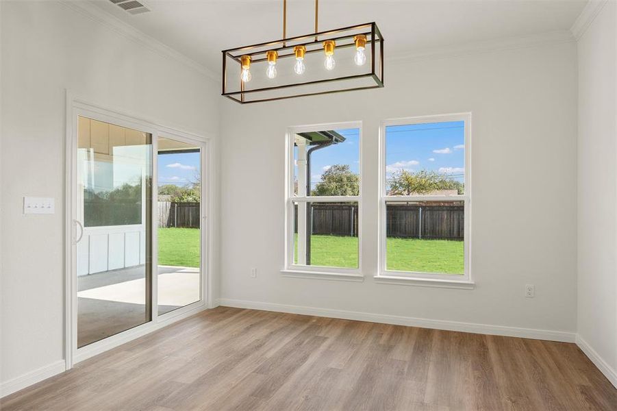 Unfurnished dining area featuring crown molding and light wood-style flooring Unfurnished dining area featuring crown molding and light wood-style flooring