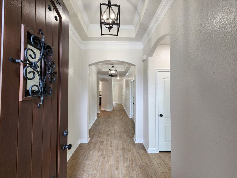 Enter this home through a grand front door, revealing a corridor with recessed lighting and elegant arched doorways. Enter this home through a grand front door, revealing a corridor with recessed lighting and elegant arched doorways.