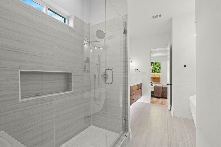 Bathroom featuring vanity, ensuite bathroom, a shower stall, a soaking tub, and a wainscoted wall