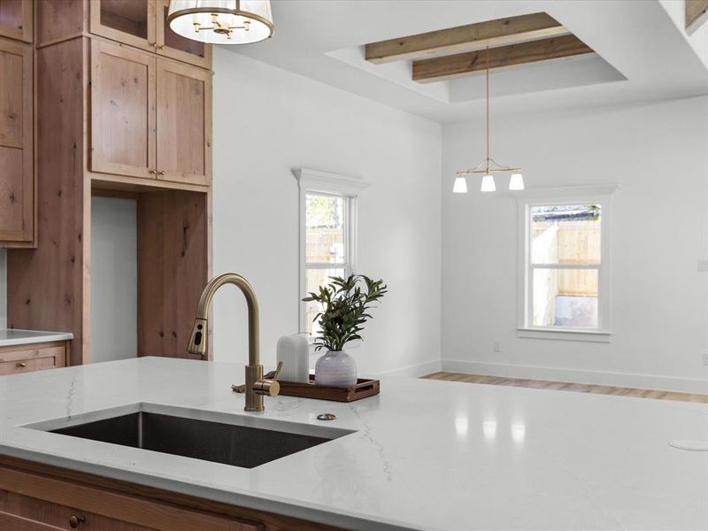 Kitchen featuring a chandelier, beamed ceiling, hanging light fixtures, wood finished floors, and light stone counters