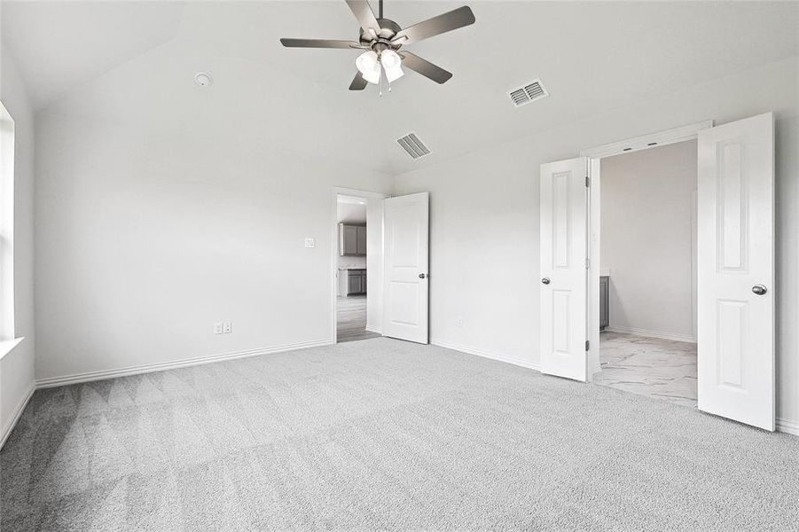 Unfurnished bedroom featuring vaulted ceiling, light colored carpet, and ceiling fan