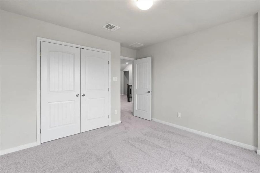 A well-lit bedroom features plush carpet flooring and classic panel doors.