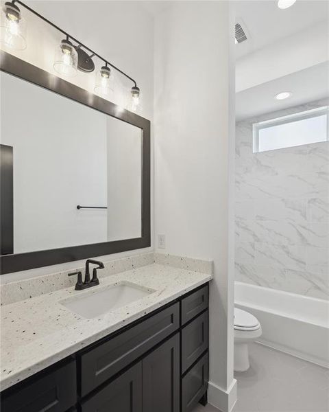 Full bathroom with tile patterned floors, toilet, tiled shower / bath combo, and vanity