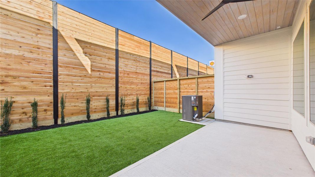 View of the backyard and the patio. The patio has ceiling fan **Photo of model home with upgrade: artificial grass, flower bed**