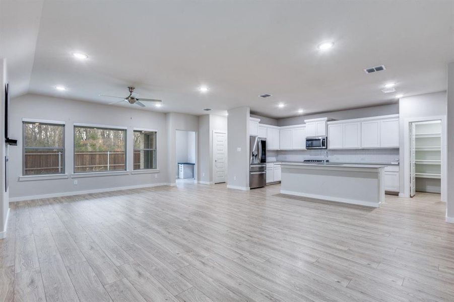 Unfurnished living room featuring light wood finished floors, ceiling fan, and recessed lighting Unfurnished living room featuring light wood finished floors, ceiling fan, and recessed lighting