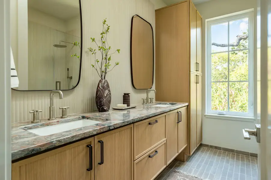 Fine stonework counters and custom cabinetry highlight this light-filled modern bath area. Fine stonework counters and custom cabinetry highlight this light-filled modern bath area.