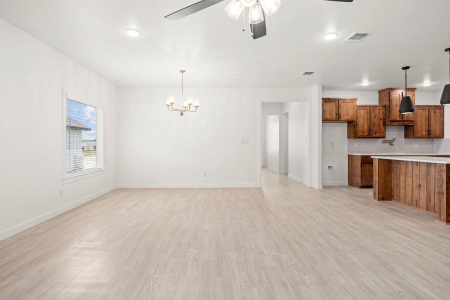 A flowing layout with light-toned flooring seamlessly connects the living and dining spaces to a modern kitchen.