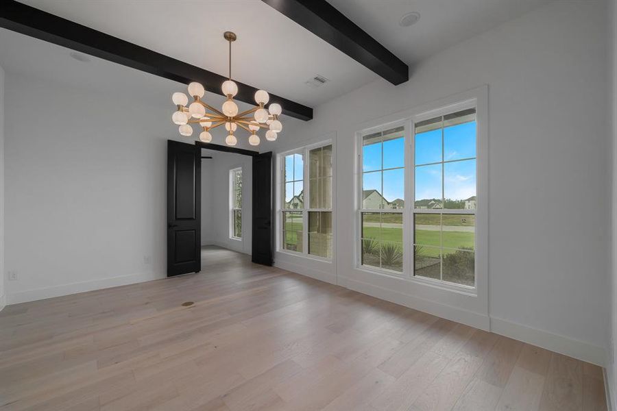 Spare room featuring a wealth of natural light, a chandelier, light hardwood / wood-style floors, and beam ceiling