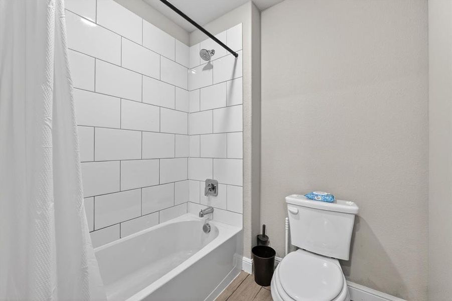 Full bathtub and shower combination featuring white subway tile surround, polished chrome fixtures, and a matte black shower rod