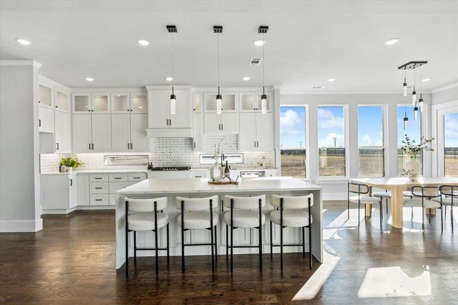 Kitchen with a kitchen island with sink, hanging light fixtures, and a healthy amount of sunlight