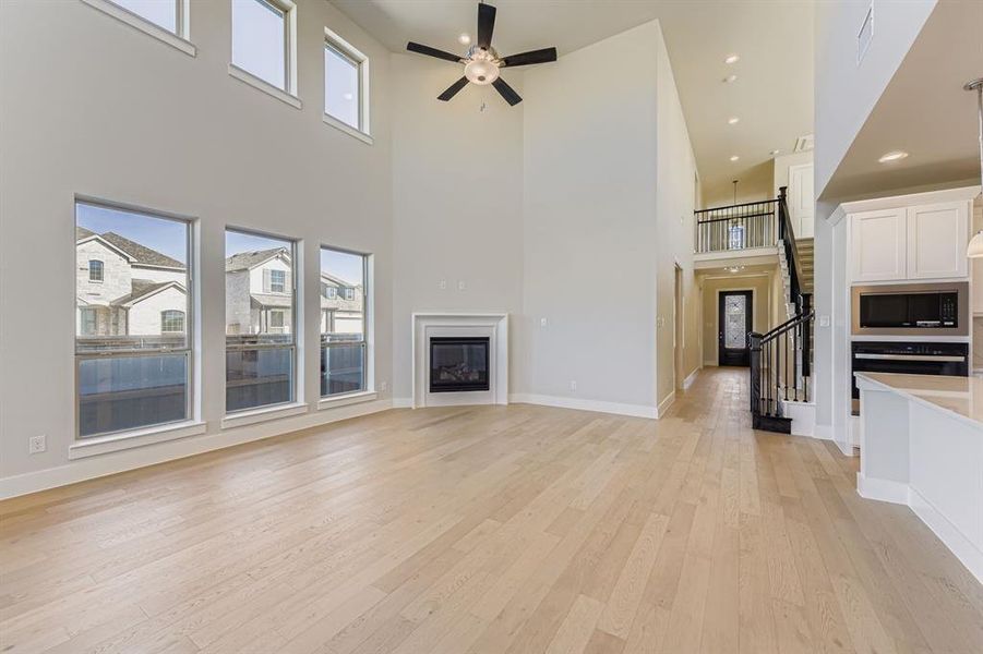 Unfurnished living room with a glass covered fireplace, healthy amount of natural light, light wood-style floors, ceiling fan, and recessed lighting