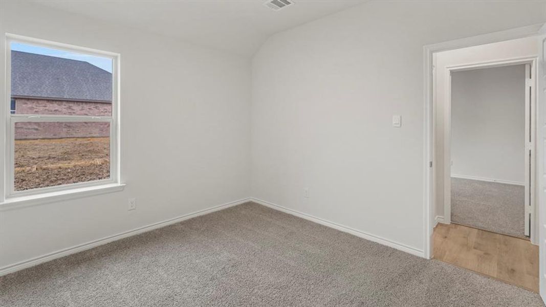 Unfurnished room with light colored carpet and lofted ceiling Unfurnished room with light colored carpet and lofted ceiling