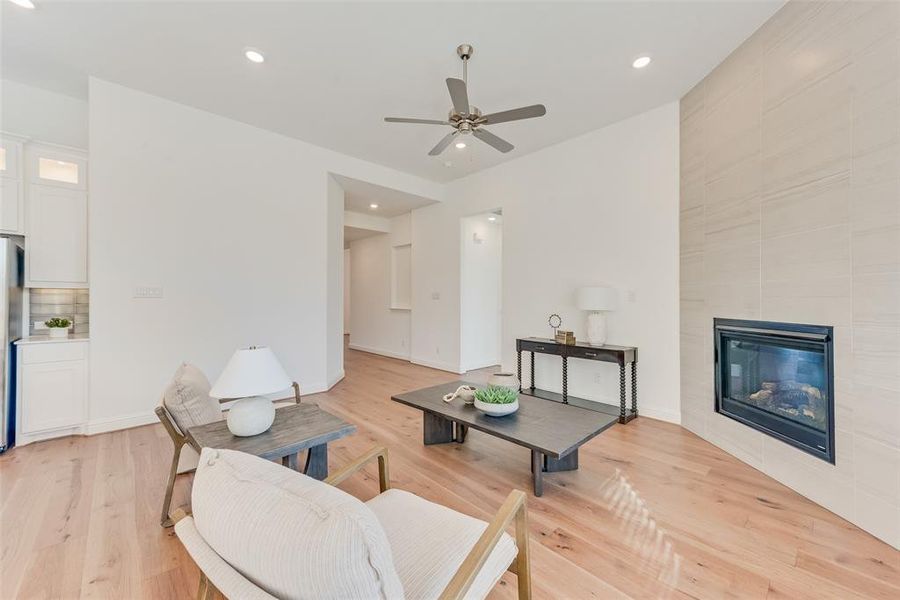 Living room featuring a tile fireplace, ceiling fan, and light hardwood / wood-style floors