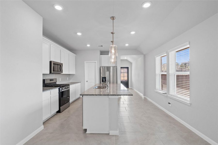The extended granite countertop creates a convenient breakfast bar, providing a casual and inviting space where stools can be added for quick meals or long conversations.