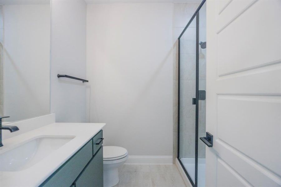 Bathroom with a shower stall, toilet, vanity, and baseboards