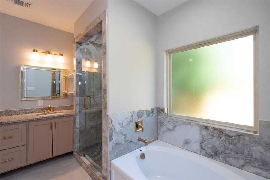 Bathroom featuring vanity, walk in shower and separate garden tub