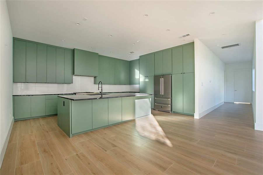 Kitchen with green cabinets, sink, backsplash, and high end fridge