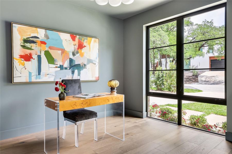 Room featuring expansive black-framed windows, light wood-finish flooring, and a contemporary light fixture