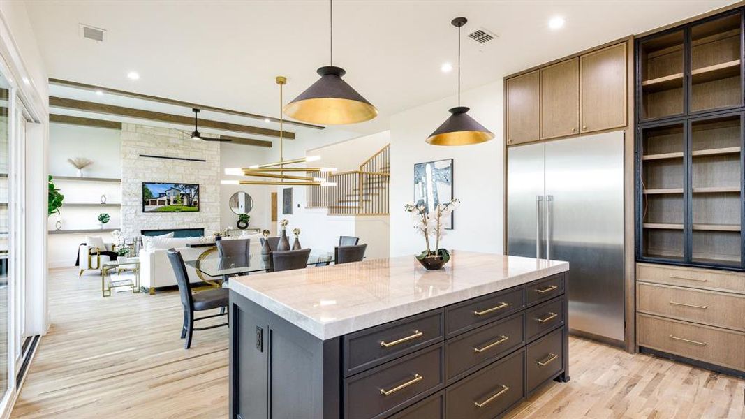 Kitchen featuring a stone fireplace, a center island, light hardwood / wood-style floors, and stainless steel built in refrigerator