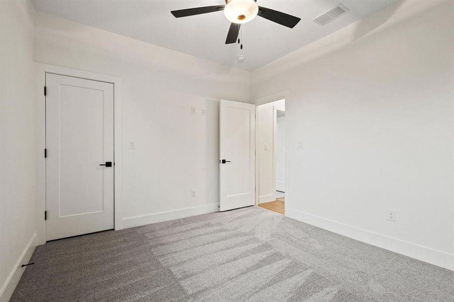 Unfurnished bedroom with light carpet and ceiling fan